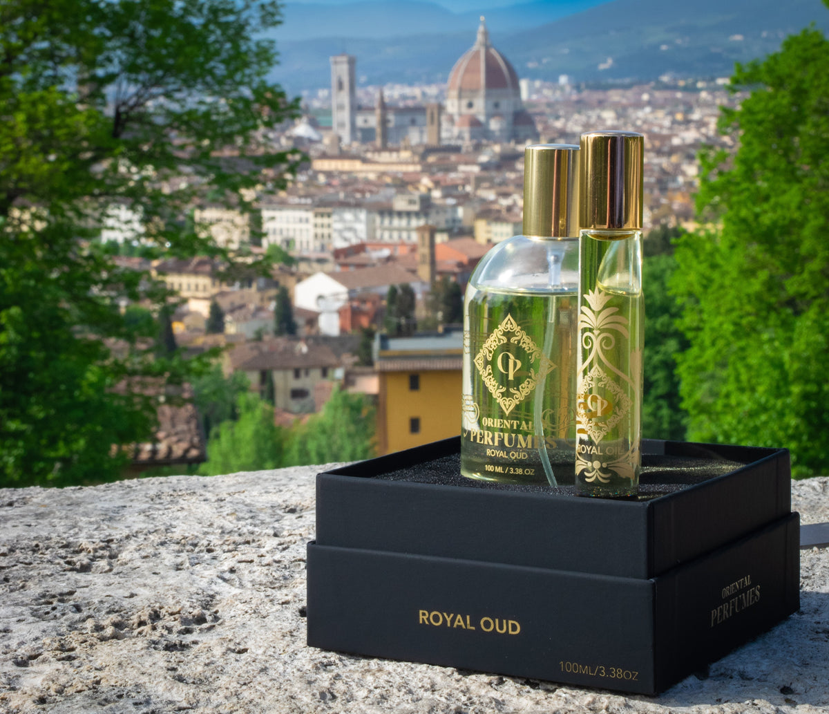 Oriental Perfumes Royal Oud 100ml spray bottle and matching perfume oil set in a luxury black and gold box, with the Florence skyline and Duomo blurred in the background.